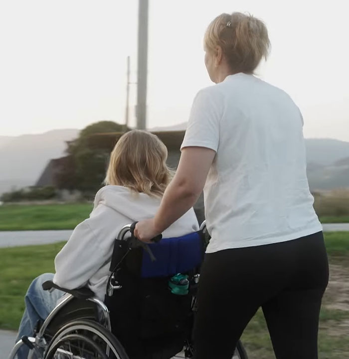Person pushing wheelchair outdoors, representing model found with broken limbs and spine on Dubai roadside. Person pushing wheelchair outdoors, representing model found with broken limbs and spine on Dubai roadside.