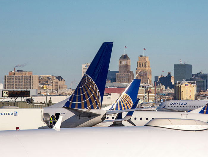United Airlines planes parked at the airport with city skyline in the background during clear daylight hours. United Airlines planes parked at the airport with city skyline in the background during clear daylight hours.