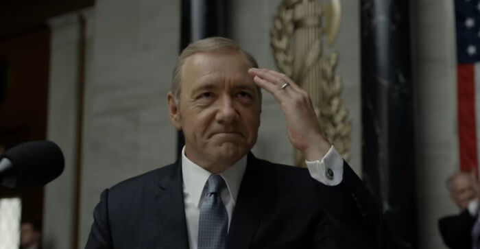 Man in a suit in a formal setting representing characters from shows that are very hard to love.