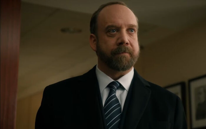 Middle-aged man in a suit with a beard, portraying a difficult character from shows with hard to love characters.