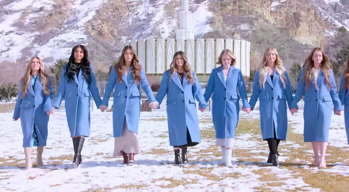 Group of women in matching blue coats holding hands outdoors with snowy mountains, representing shows with hard to love characters