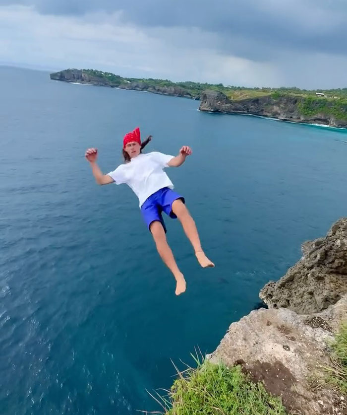 21-year-old daredevil mid-air diving off cliff into ocean attempting a record-breaking stunt over clear water. 21-year-old daredevil mid-air diving off cliff into ocean attempting a record-breaking stunt over clear water.