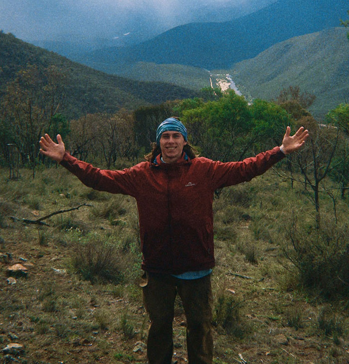 21YO daredevil in a red jacket standing with arms outstretched in a mountainous outdoor setting before record-breaking dive footage 21YO daredevil in a red jacket standing with arms outstretched in a mountainous outdoor setting before record-breaking dive footage