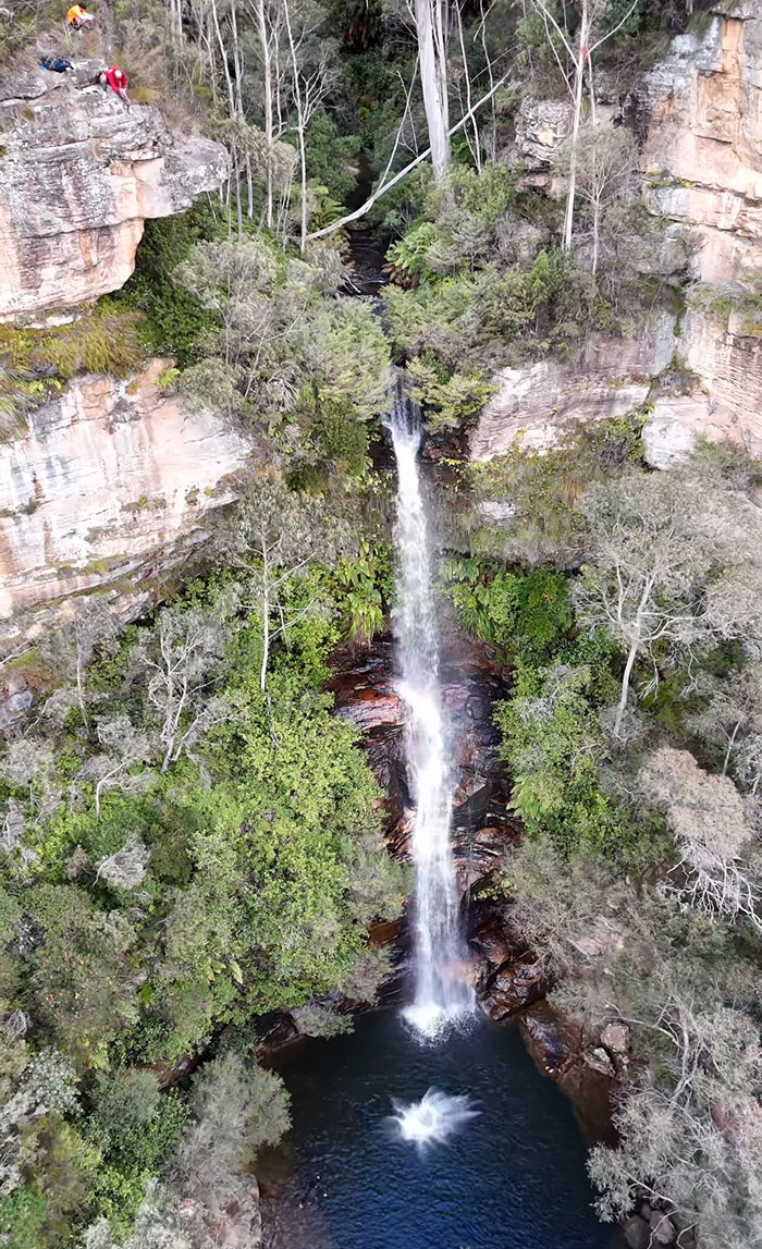 Aerial view of a waterfall with a splash in the pool below as a 21YO daredevil attempts a record-breaking dive. Aerial view of a waterfall with a splash in the pool below as a 21YO daredevil attempts a record-breaking dive.