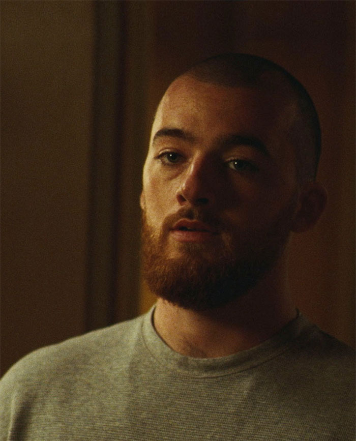 Fezco with a beard and shaved head, wearing a gray shirt, representing rare boy names for stand-out babies.