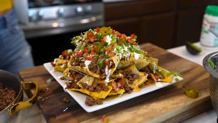 Plate of loaded nachos with meat, cheese, and toppings illustrating trends leading to overconsumption in food culture.