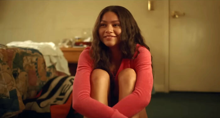 Actress sitting on the floor smiling, in a casual indoor setting, related to celebrities many people love but can't stand.