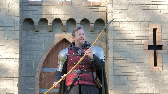 Person dressed as a medieval knight standing outside a stone castle, symbolizing people share unsubscribed YouTubers.