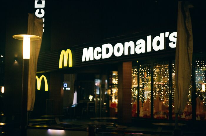 McDonald's restaurant exterior at night with illuminated golden arches and employees sharing bizarre experiences.