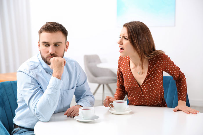 Bride protests to change caterer while groom looks upset during a tense wedding planning discussion at home. Bride protests to change caterer while groom looks upset during a tense wedding planning discussion at home.