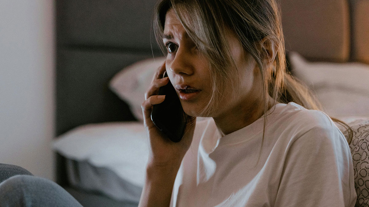 Worried wife talking on phone at home, fearing husband is lost at sea while facing heartless mother-in-law conflict.