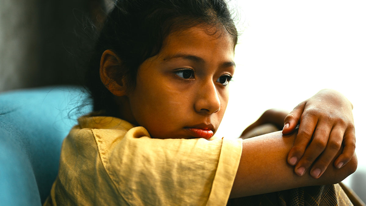 Sad young girl sitting alone, reflecting on family and adoption challenges during a difficult divorce and custody dispute.