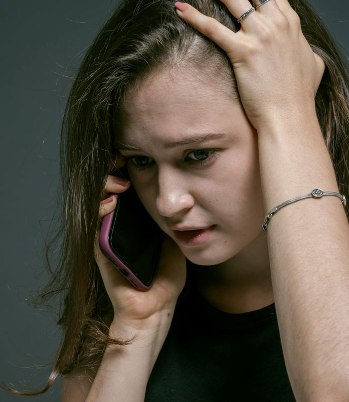 Young woman looking distressed while talking on phone, reflecting on cutting off friend in abusive marriage situation. Young woman looking distressed while talking on phone, reflecting on cutting off friend in abusive marriage situation.