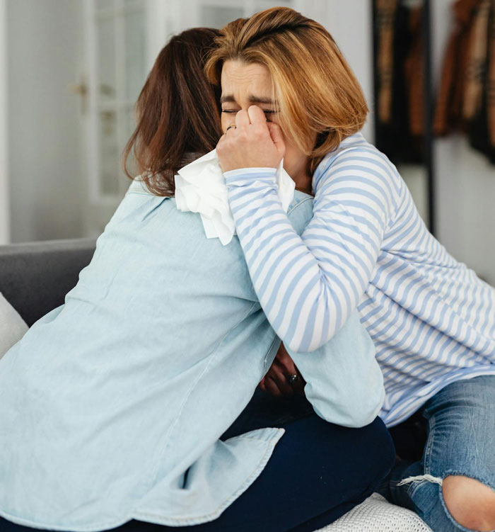 Two women comforting each other, one crying and holding tissues, reflecting on staying in an abusive marriage and friendship struggles. Two women comforting each other, one crying and holding tissues, reflecting on staying in an abusive marriage and friendship struggles.