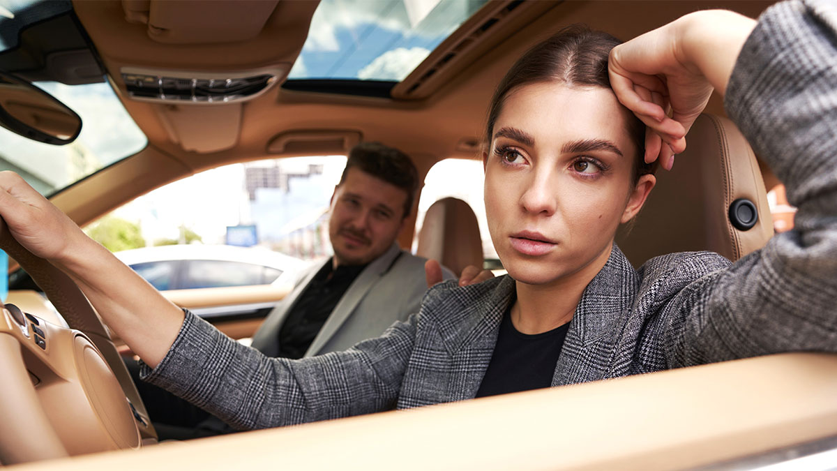 Woman looking frustrated in car with man in the passenger seat after a tense moment on the road during a date.