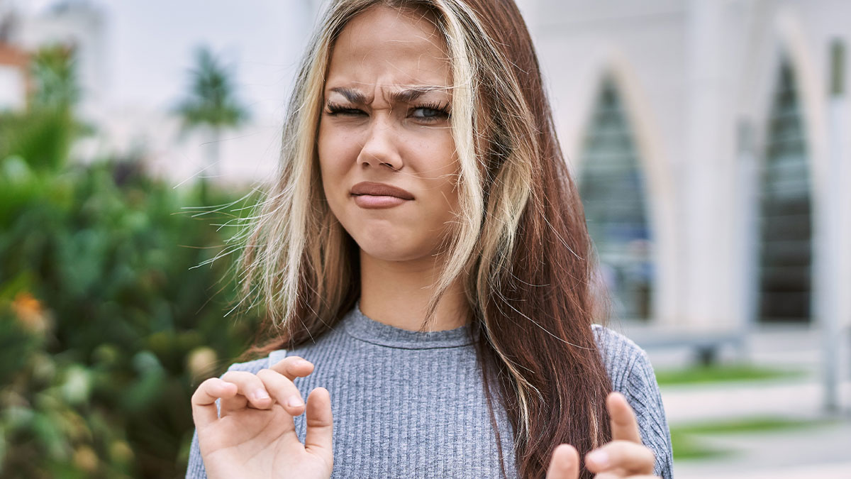 Young woman outdoors showing discomfort reacting to inappropriate comments from men in public spaces