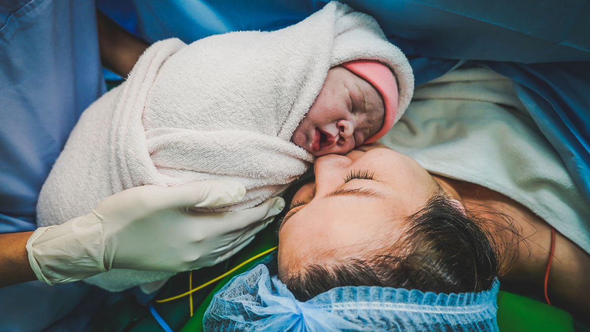 Newborn baby wrapped in a blanket held by a medical professional, highlighting behaviors related to toxic femininity.