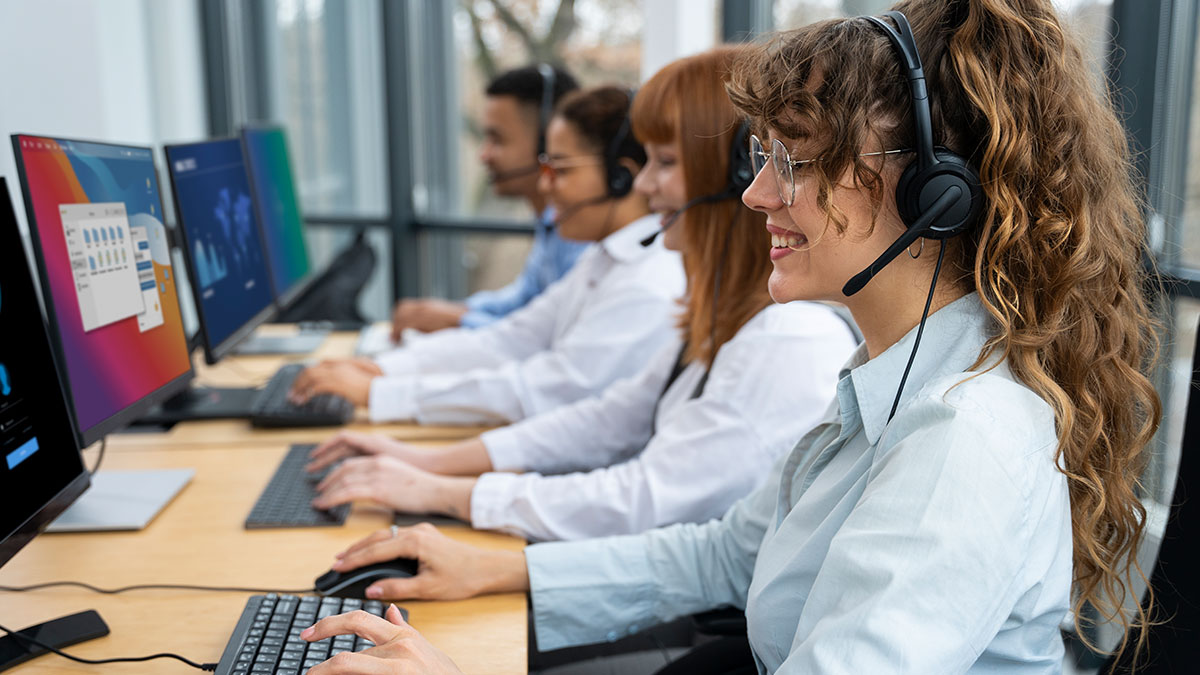 New supervisor and call center agents wearing headsets working at computers in a bright office environment.
