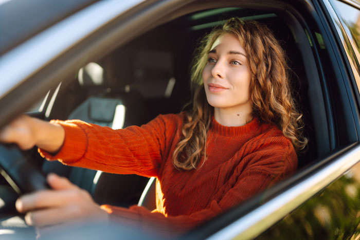 Woman driving car looking thoughtful, illustrating coworker moving in and demanding rides without notice or tact.