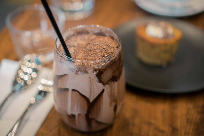 Close-up of a chocolate milkshake with a straw on a table, related to McDonald's employees sharing bizarre experiences.