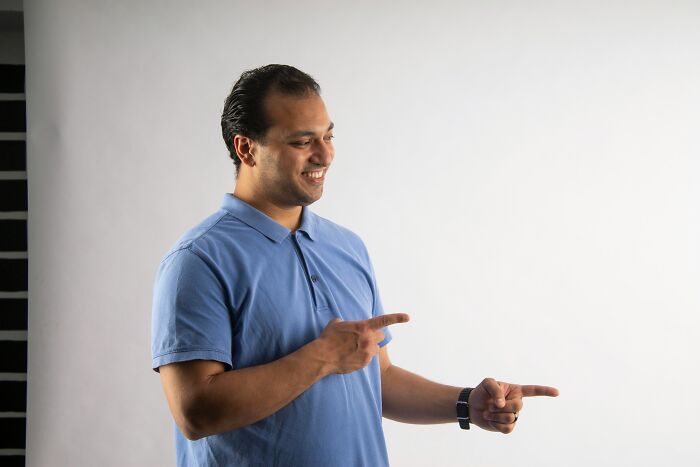 Man in a blue polo shirt smiling and pointing to the side illustrating bizarre beliefs people still fall for myth busted