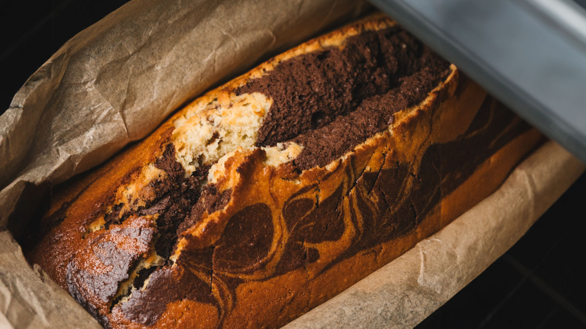 Freshly baked childhood cake with rich chocolate swirls cooling on parchment paper in a loaf pan after son's hospital trip.