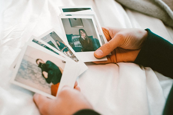 Hands holding several printed photos, reflecting on past memories related to husband and his ex in a personal setting. Hands holding several printed photos, reflecting on past memories related to husband and his ex in a personal setting.