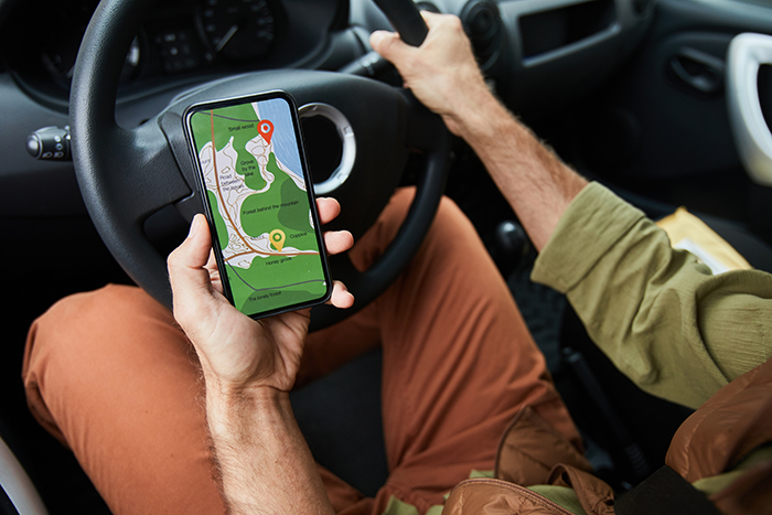Man driving a car holding a phone with GPS navigation, possibly searching to find a woman who missed fiancé’s calls. Man driving a car holding a phone with GPS navigation, possibly searching to find a woman who missed fiancé’s calls.