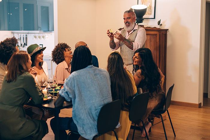 Group of friends enjoying a relaxed childfree event indoors with laughter and conversation around a dining table. Group of friends enjoying a relaxed childfree event indoors with laughter and conversation around a dining table.