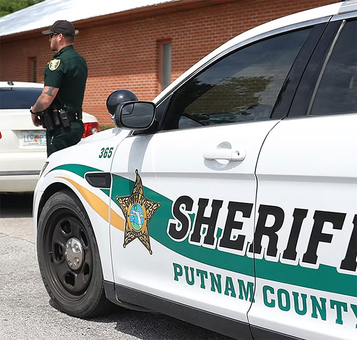 Putnam County sheriff car with officer standing nearby, related to Florida mother abandoning child and seven dogs case. Putnam County sheriff car with officer standing nearby, related to Florida mother abandoning child and seven dogs case.