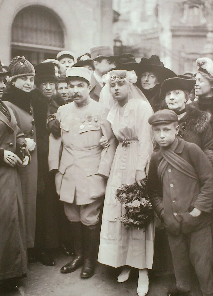Vintage historical photo of a bride and decorated soldier surrounded by family, capturing a heartfelt moment from the past.