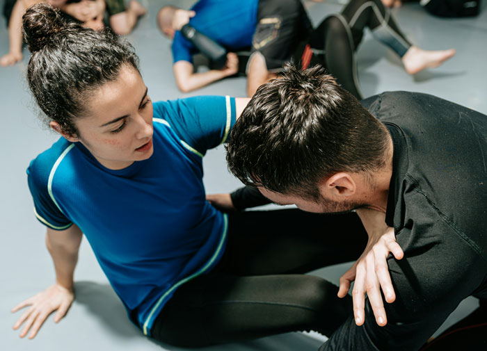 Two adults practicing self-defense techniques in a group class focused on safety and protection skills. Two adults practicing self-defense techniques in a group class focused on safety and protection skills.