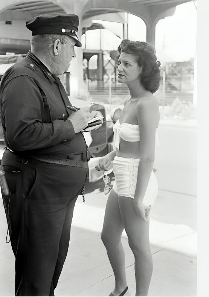 Police officer writing a ticket for a young woman in vintage swimwear in a historical photo with interesting backstory.