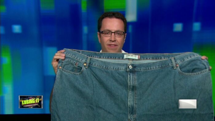 Man holding oversized jeans in a TV studio setting, illustrating surprising videos with hidden context.