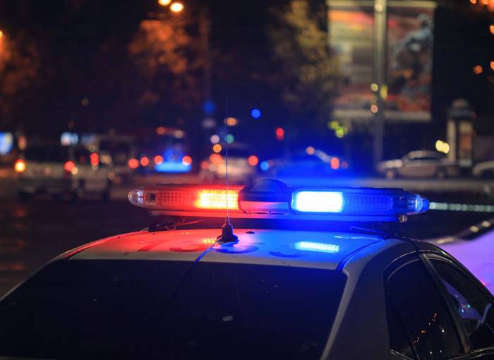 Police car with flashing red and blue lights at night responding to a dog attack involving a stalker incident. Police car with flashing red and blue lights at night responding to a dog attack involving a stalker incident.