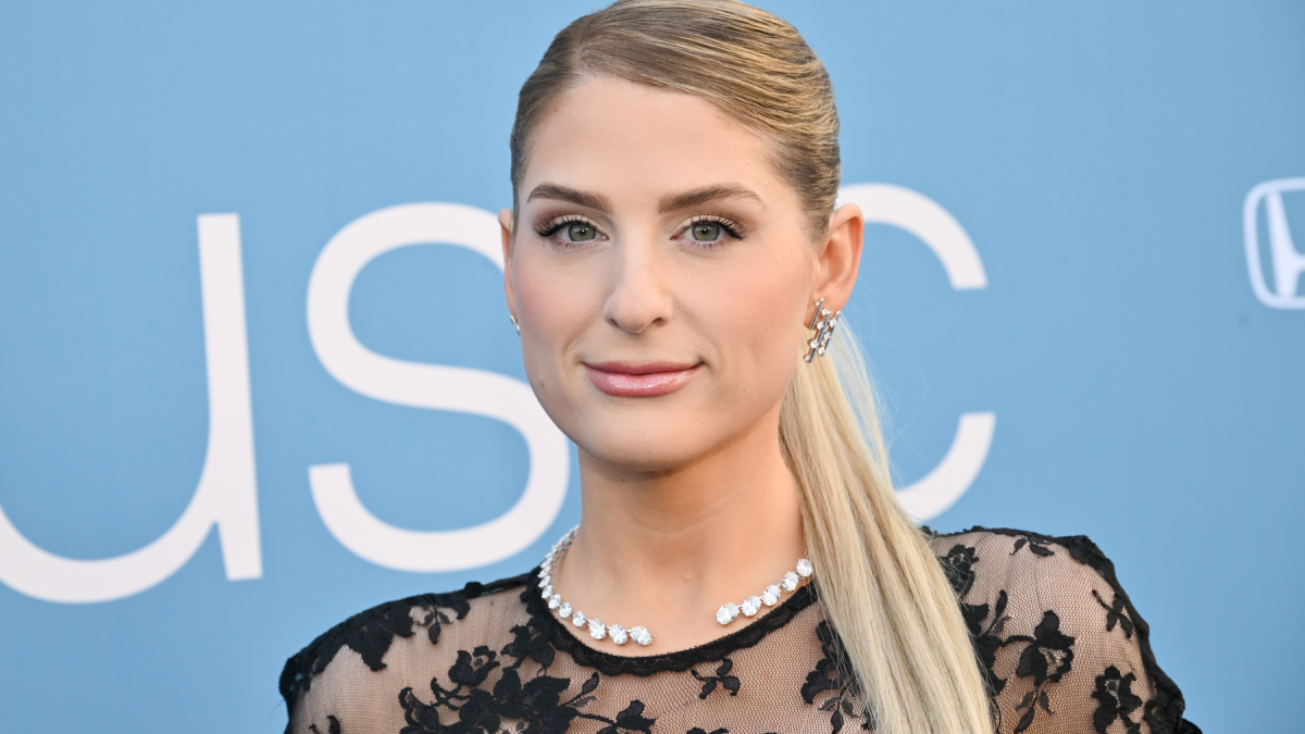 Blonde woman with sleek ponytail and natural makeup showcasing subtle lip flip look at a public event.