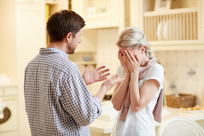 Couple arguing in kitchen, woman covering face in distress, representing conflict over husband and his ex relationship issues. Couple arguing in kitchen, woman covering face in distress, representing conflict over husband and his ex relationship issues.