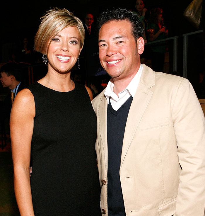 Kate and Jon Gosselin smiling at a social event with people in the background, dressed in formal attire. Kate and Jon Gosselin smiling at a social event with people in the background, dressed in formal attire.