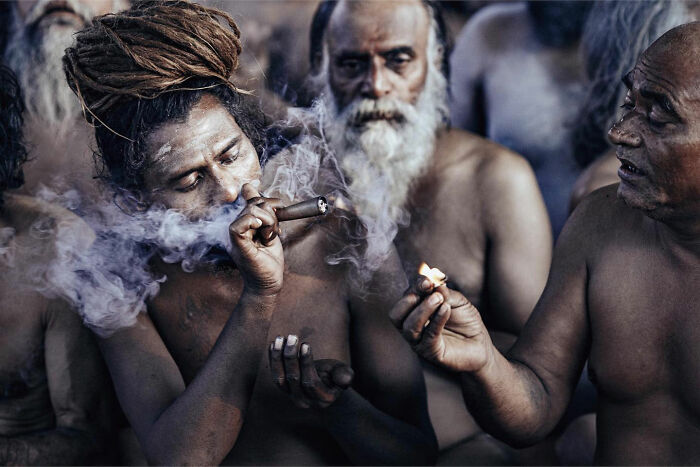 Candid everyday moment in Asia showing men sharing smoke in a traditional setting, captured by photographer Gil Kreslavsky.