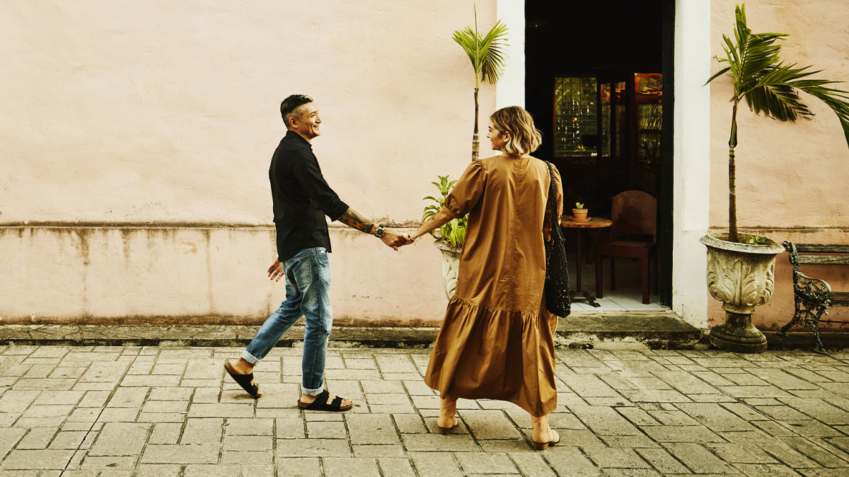 Couple holding hands and walking outside a building, representing mood-based questions to ask your crush concept.
