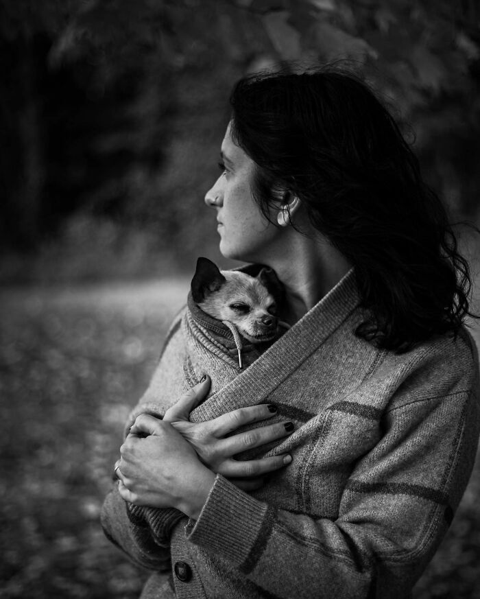 Woman gently holding and comforting her small dog, capturing touching final moments between pets and their humans in black and white.