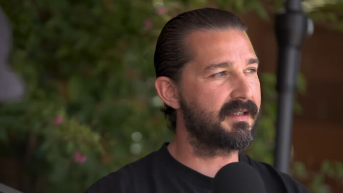 Man with beard and slicked-back hair speaking into a microphone in a casual setting about celebrities Hollywood tried to make leading A-listers