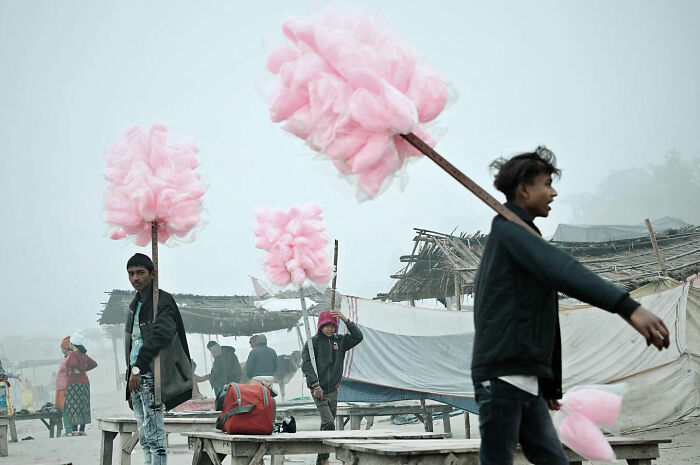 Young men carrying pink cotton candy in a foggy Asian market, capturing candid everyday moments from Asia.