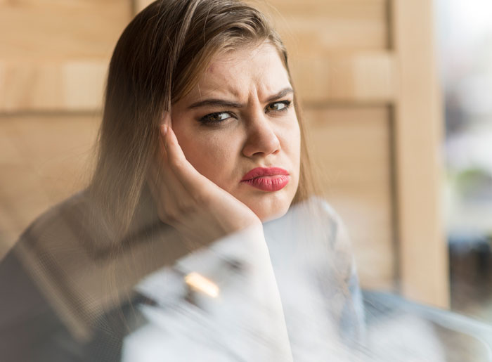 Woman with a frustrated expression resting her face on her hand, reflecting family demands and financial conflict. Woman with a frustrated expression resting her face on her hand, reflecting family demands and financial conflict.