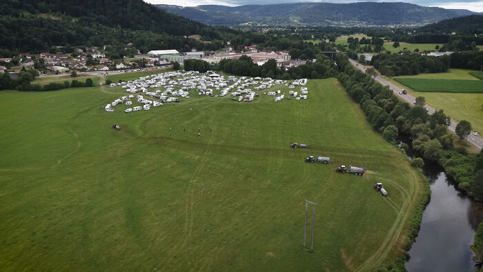 Aerial view of a large field with tractors spraying manure near campers and squatters during a viral farmer incident. Aerial view of a large field with tractors spraying manure near campers and squatters during a viral farmer incident.