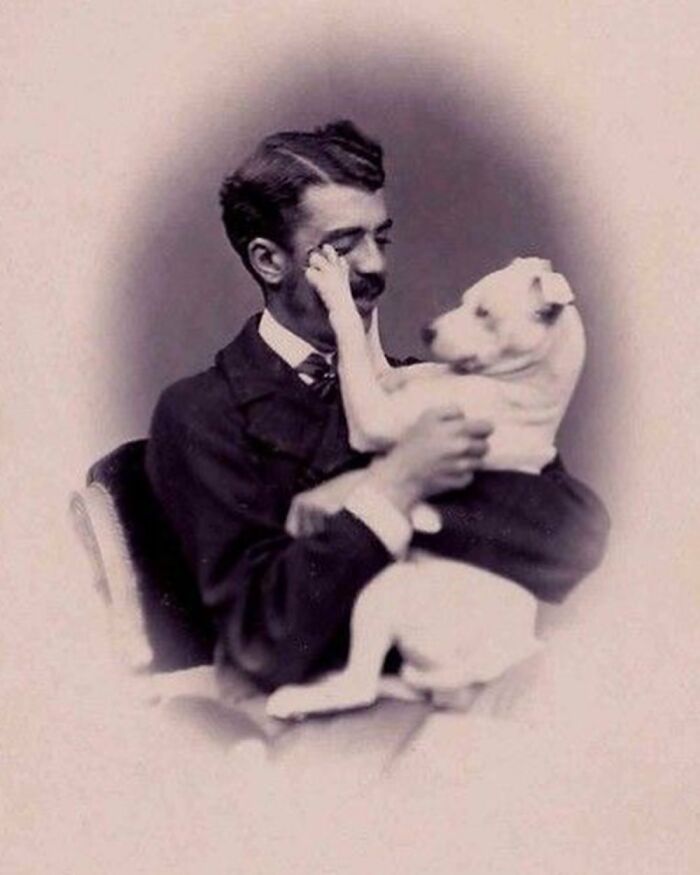 Victorian man with mustache holding a dog, showcasing the charm of handsome Victorian men in a vintage portrait.