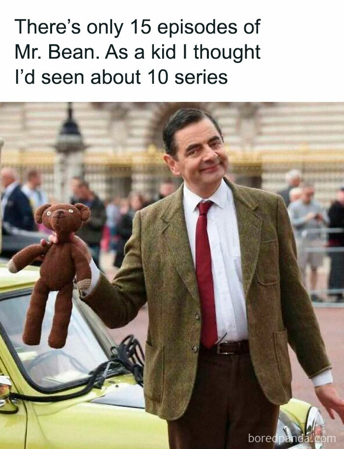 Man dressed as Mr. Bean holding a teddy bear, standing next to a vintage car, representing chaotic British memes.