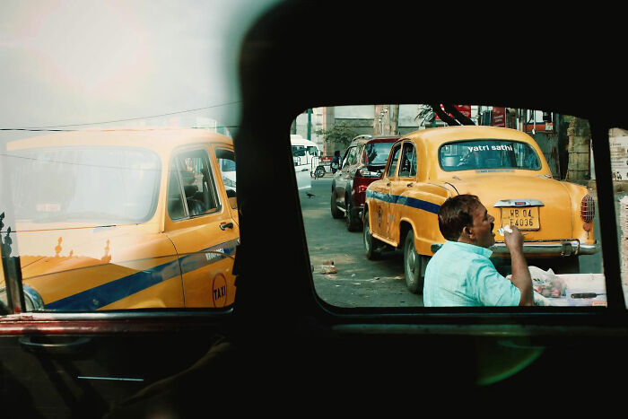 Candid everyday moments in Asia showing a man beside yellow taxis on a busy street captured by photographer Gil Kreslavsky.