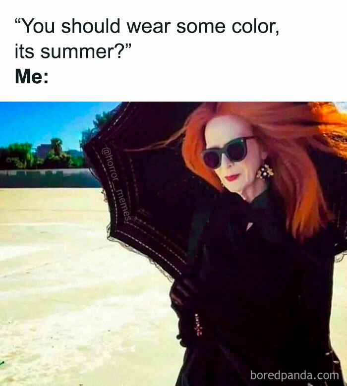 Woman with red hair wearing black clothes and sunglasses holding an umbrella in the sun, representing introvert-worthy memes.