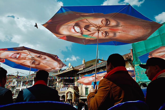Colorful umbrellas with smiling faces held by people in a busy street scene from candid everyday moments in Asia photography.